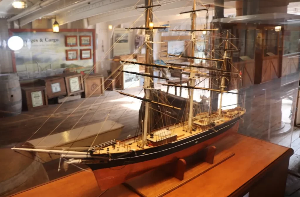 Historical wooden ship model in a glass display case.