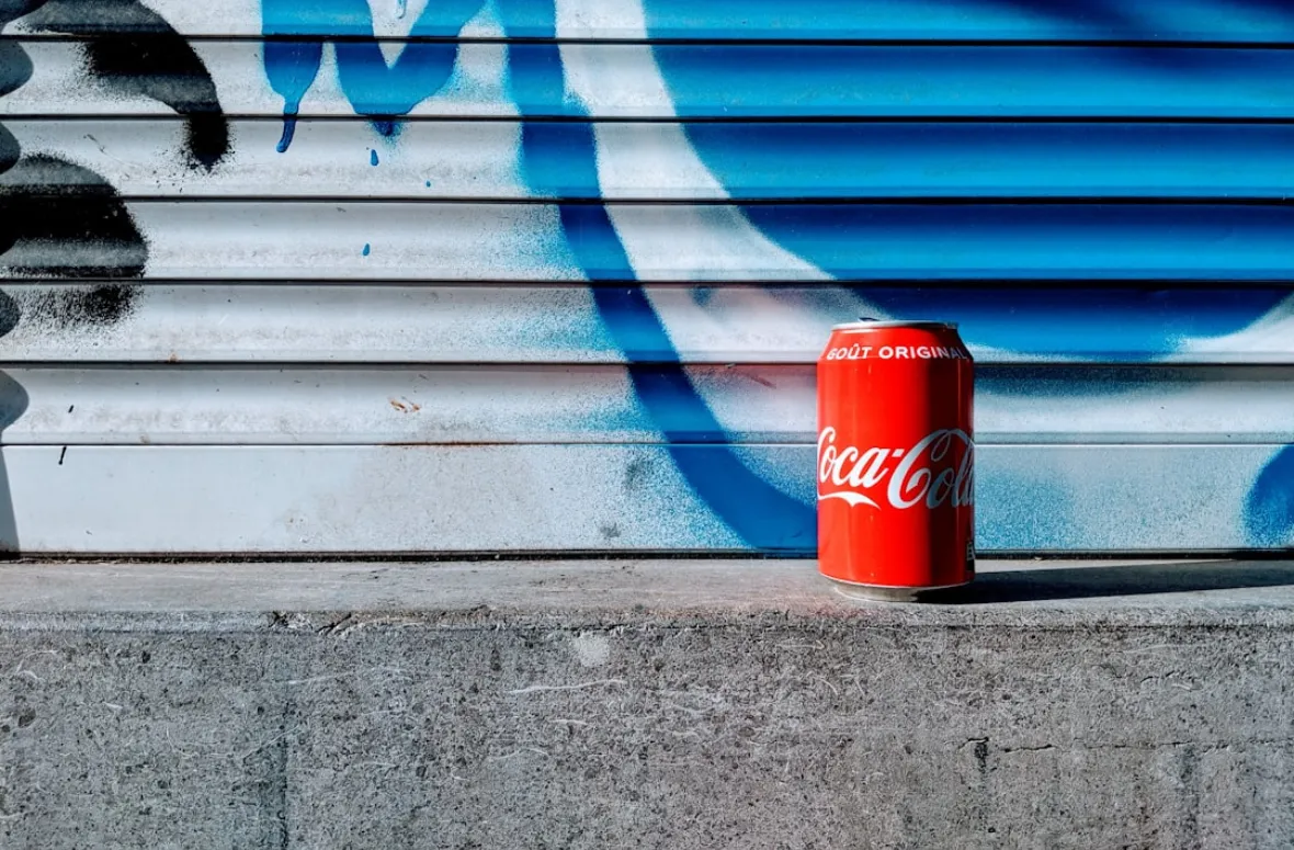 Coca-Cola can against a graffiti background with drink info.